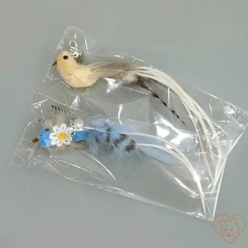 Two colorful feather cat toy attachments in a clear packaging, featuring a bird and a blue plush toy with flowers.