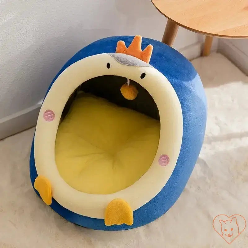 Semi-enclosed plush cat bed in blue with a cute penguin design, offering cozy retreat for cats.