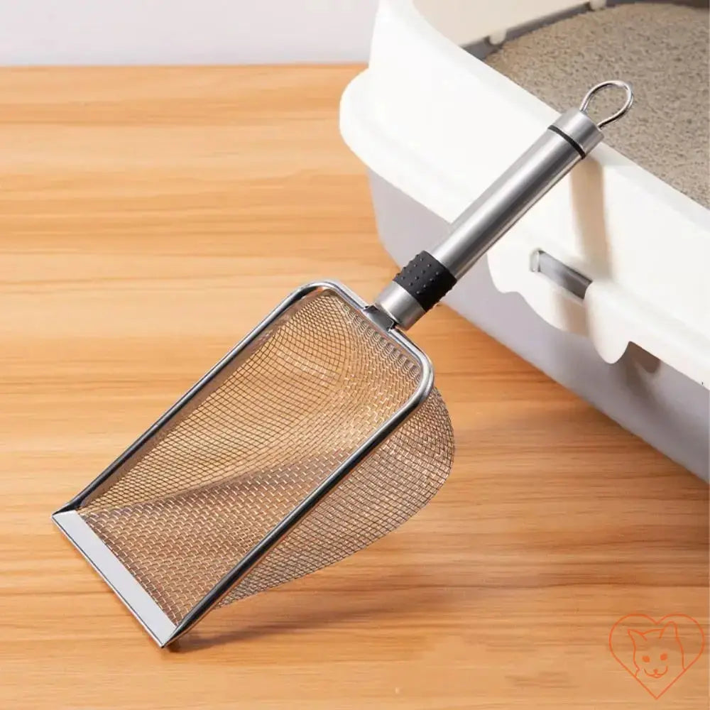 Aluminum alloy cat litter scoop with mesh design on wooden surface next to litter box, showcasing durability and lightweight features.