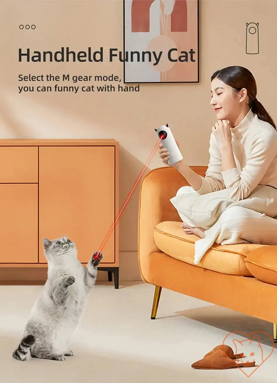 Woman using a handheld LED laser toy to play with a cat indoors on a cozy orange sofa.