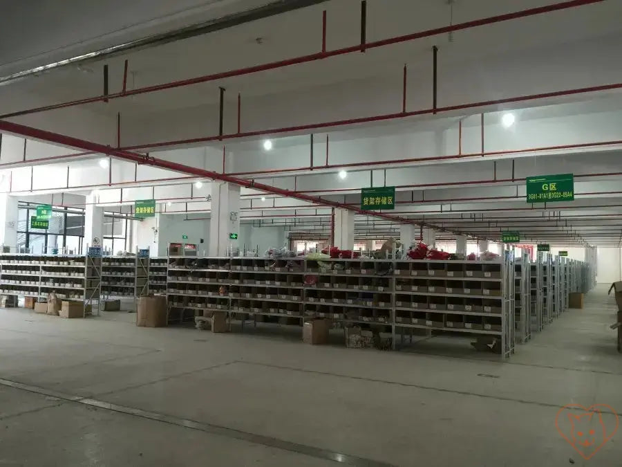 Interior view of a spacious warehouse with shelves and organizational signage for efficient inventory management.