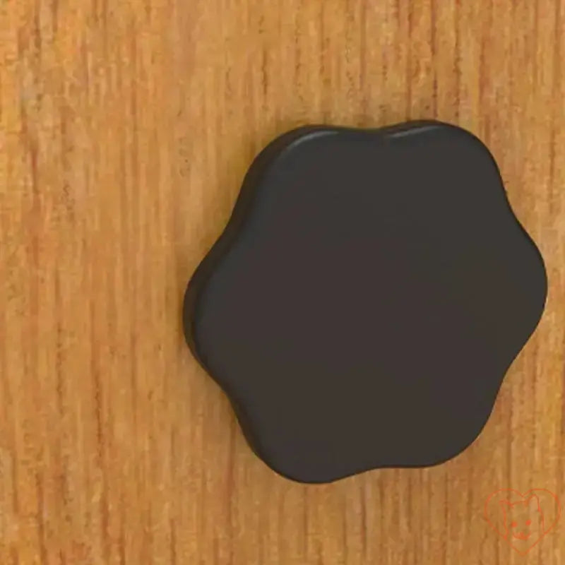 Black flower-shaped knob on wooden surface for home decor or cabinet use.