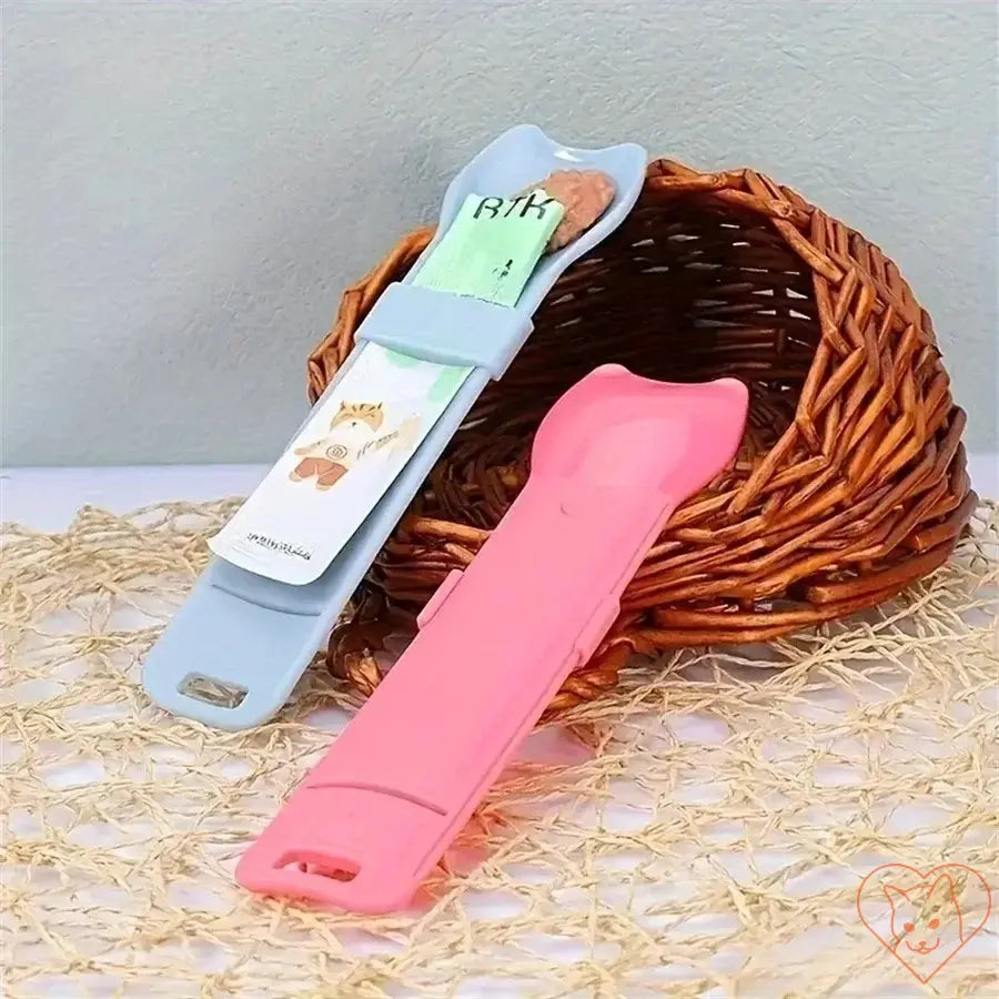 Colorful cat strip squeeze spoons designed for lickable wet cat treats, placed next to a woven basket.