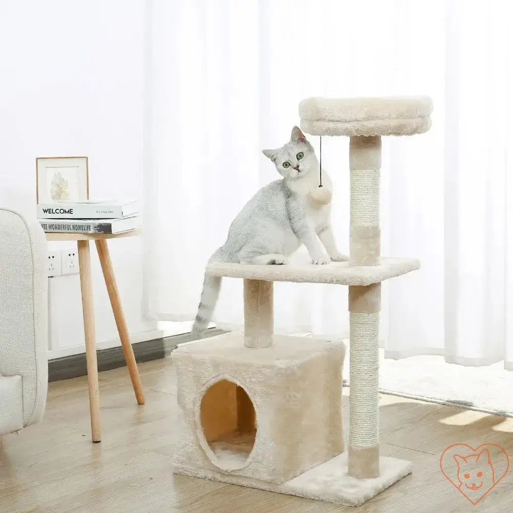 Cat sitting on a multi-level cat tree house tower with scratching posts and a cozy hammock.