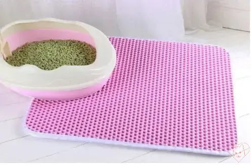 Double-layer waterproof cat litter mat in pink next to a cat litter box, designed to trap litter and prevent mess.