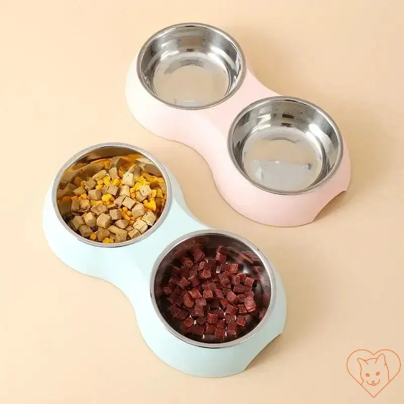 Double stainless steel pet food bowl set with pastel pink and blue bases, featuring dog food and treats.