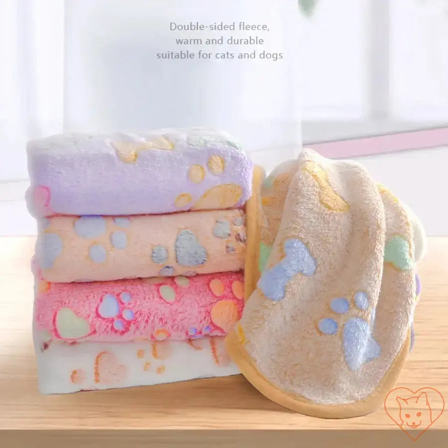 Colorful stack of double-sided fleece pet blankets with paw prints, ideal for cats and dogs, warm and durable.