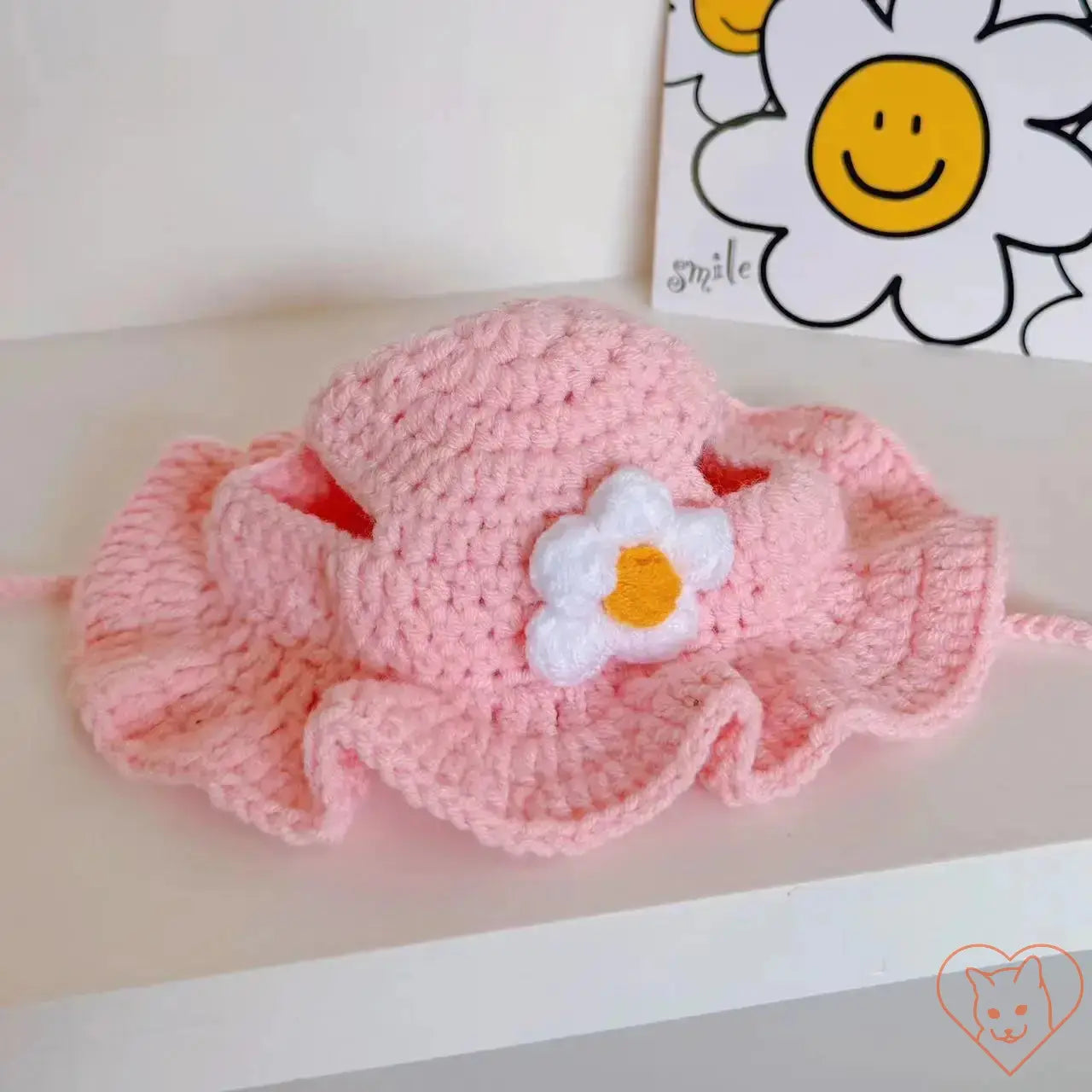 Hand-knitted pink cat hat with flower detail, perfect travel accessory for stylish pets.