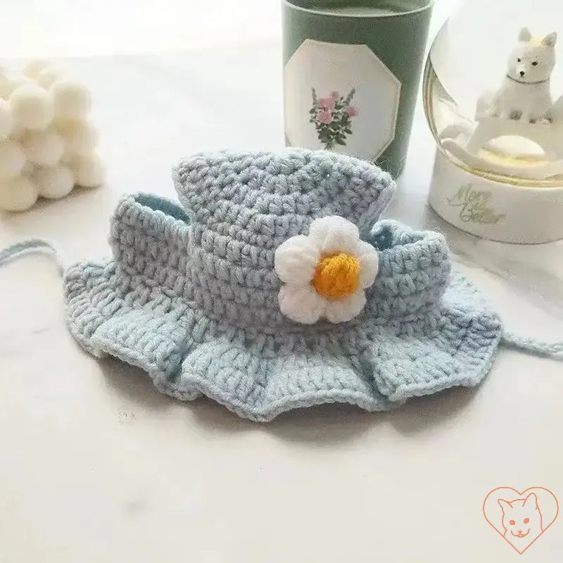 Hand-knitted light blue cat hat with daisy flower design, ideal for pet travel and special occasions.