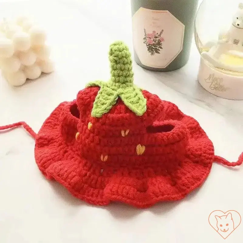 Hand-knitted red cat hat designed like a strawberry with green leaves, perfect for stylish pet accessories.