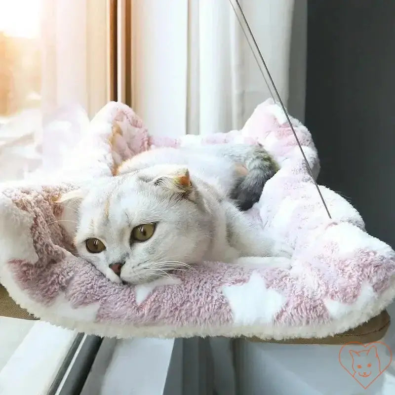 Cozy cat lounging in a pink and white hanging hammock by the window, enjoying the sunny view.