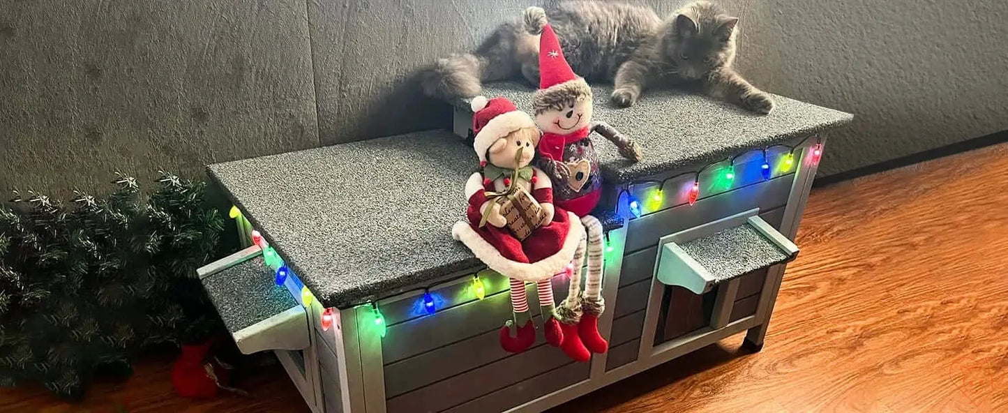 Insulated outdoor cat house decorated with holiday lights and plush toys, providing a cozy winter shelter for cats.