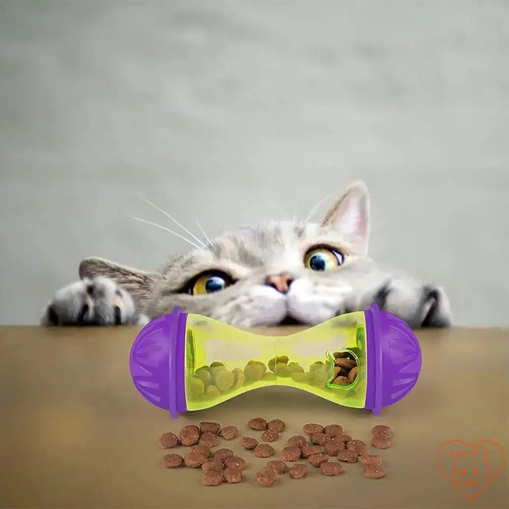 Interactive Cat Food Dispenser Toy with dry cat food, a curious cat peeking over a table.