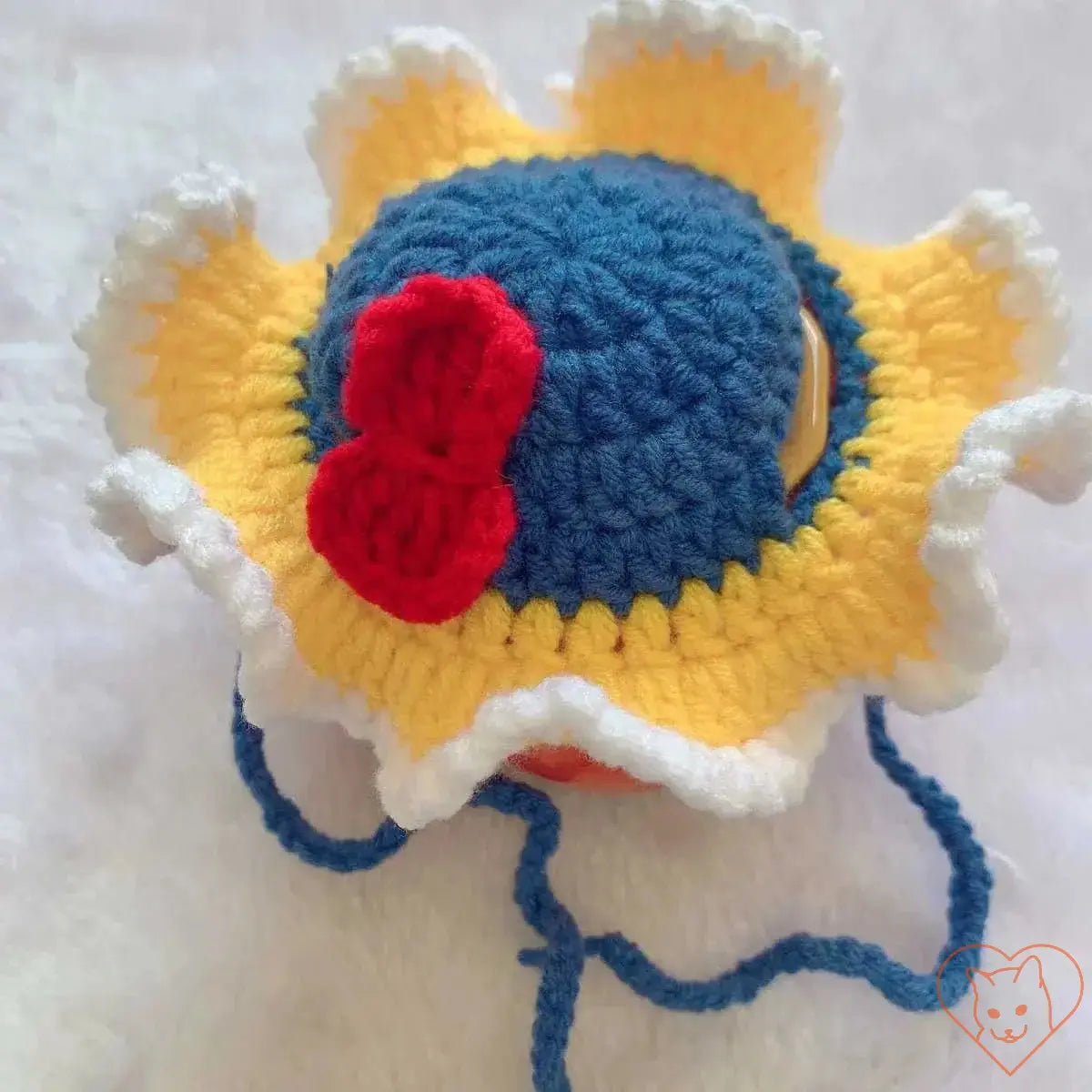 Colorful knitted cat hat with a blue top, yellow petals, and a red bow, perfect for keeping pets stylish and warm.