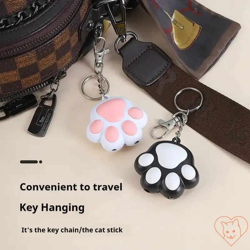 Laser Cat Teaser keychain in pink and black paw shapes, perfect for travel and fun playtime with cats.