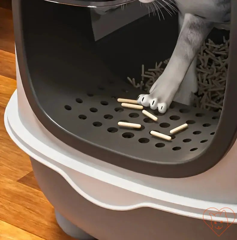 Close-up of a cat's paw inside a gray litter box with pellets, showcasing the leak-proof foldable design and hygiene features.