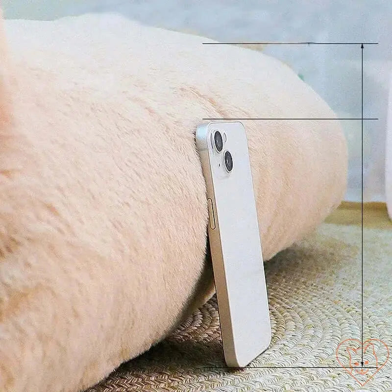 Close-up of a soft, plush cat bed with a smartphone resting against it on a cozy surface.