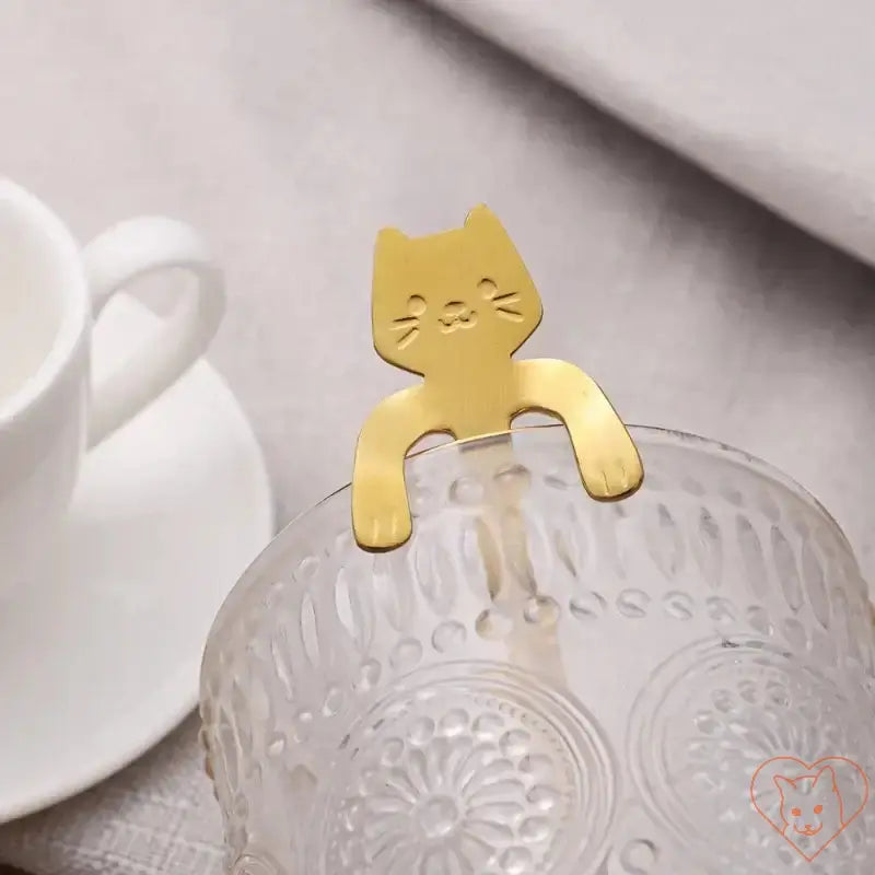 Gold cat-shaped utensil perched on a glass, perfect for adding charm to drinks and desserts.