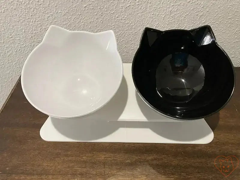 Non-slip double cat bowl in black and white with cat-ear design on a white stand for comfortable feeding.