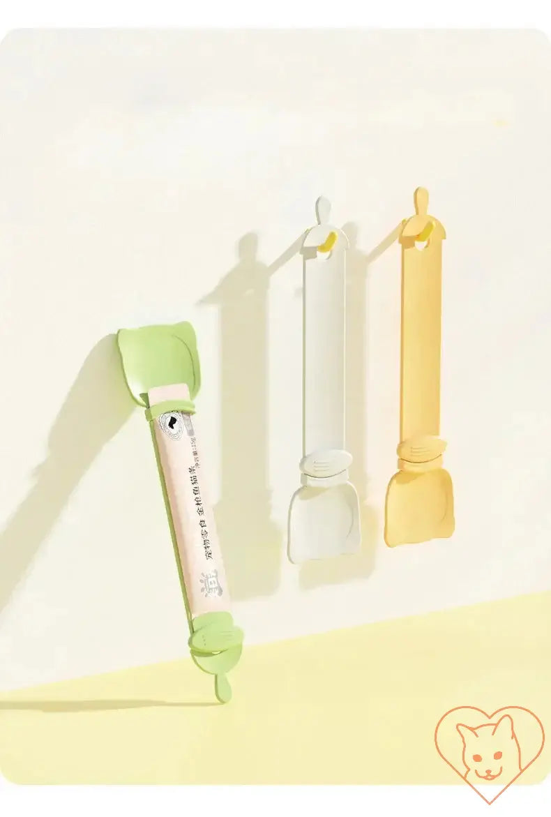 Three multifunctional pet feeder spoons in pastel colors for dispensing wet food, featuring green, white, and yellow designs.