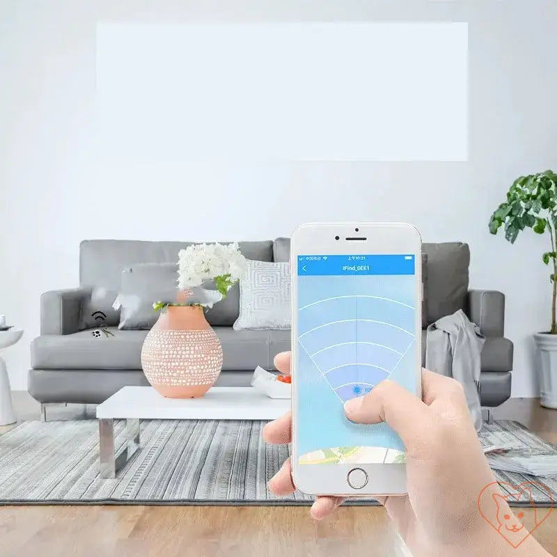 User tracking a cat with a smartphone app in a cozy living room, showcasing the Pet Tracking Locator device.