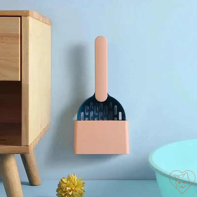 Plastic cat litter scoop with base hanging on wall, designed for convenient storage and easy cleaning.