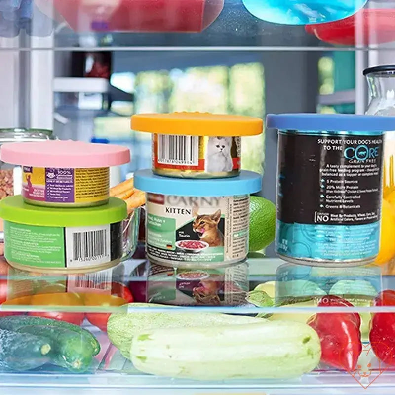 Assorted pet food cans sealed with colorful silicone lids in a fridge, showcasing freshness and odor prevention.