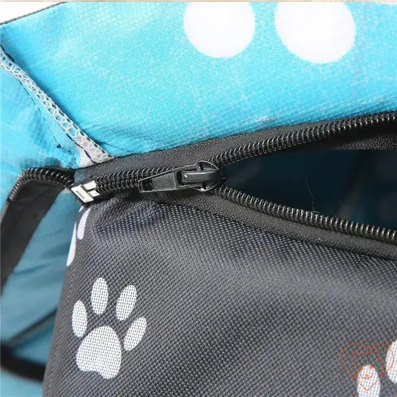 Close-up of the zipper on a waterproof outdoor cat house with paw print design and blue fabric.